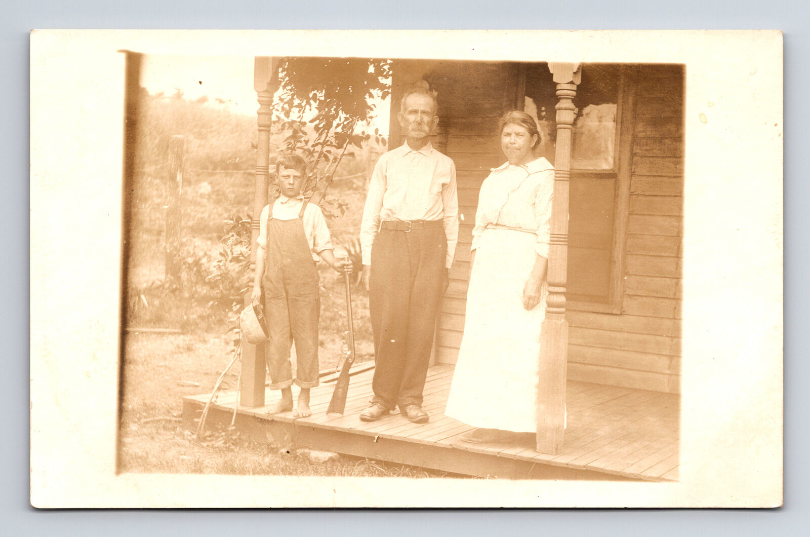 1900s RPPC Rustic Family Portrait Farm Homestead Boy With Rifle Helmet Postcard