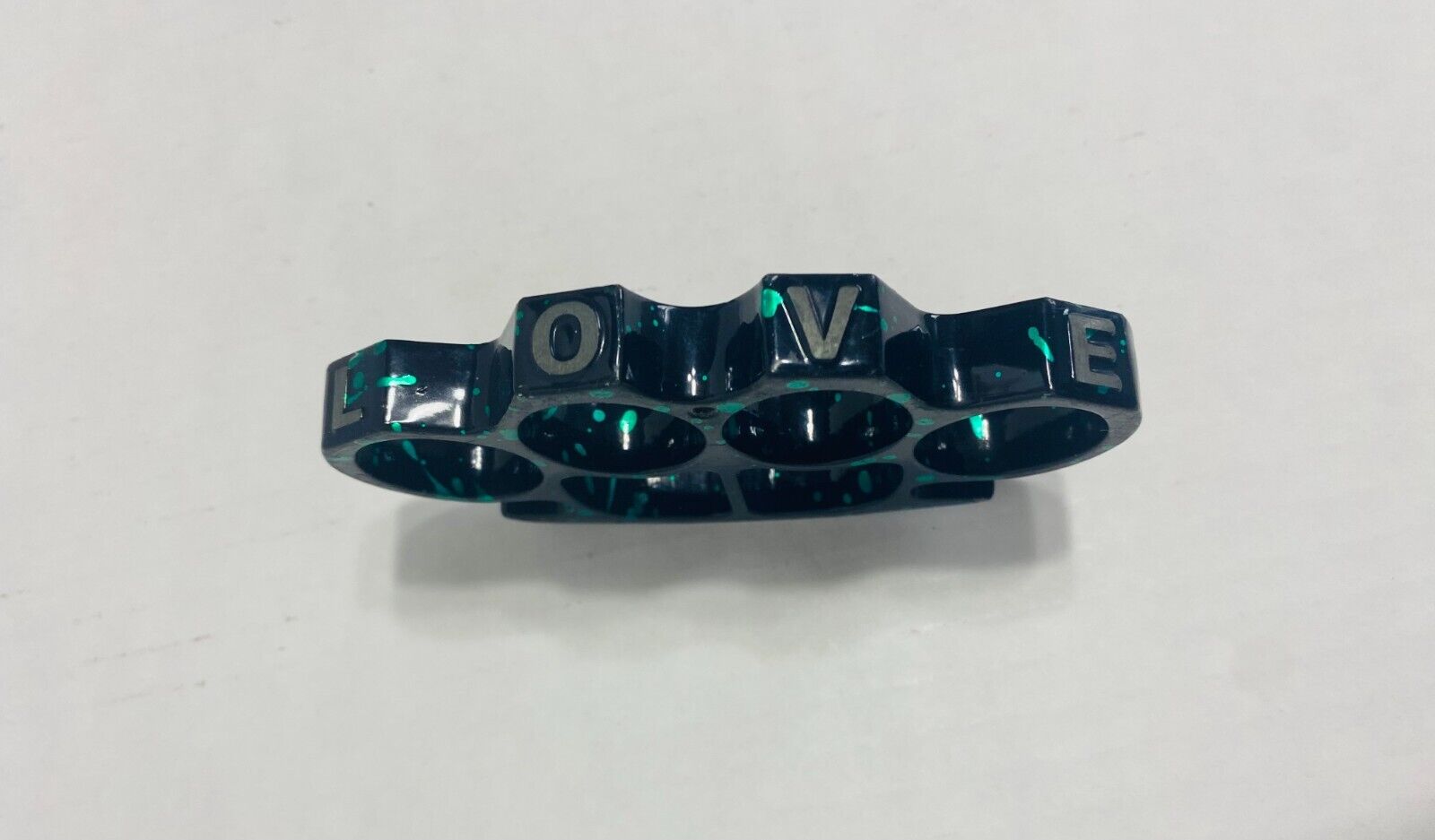 Vintage Black Metal Nuckles with Green Splatter and the word L O V E on them.