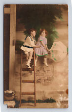 RPPC Hand Colored Portrait Boy Climbs Ladder to Flirt With Girl Postcard picture